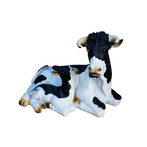 Cartoon deco figure of a motley white black colored resting cow with golden hooves 60cm