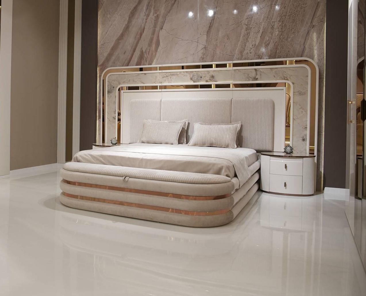 White bedroom set made of wood with bed, nightstands, and bench.