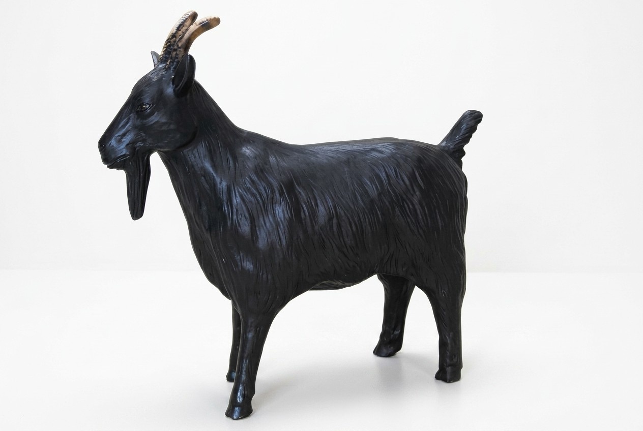 Decorative sculpture designed as gloss full black colored shaggy old goat