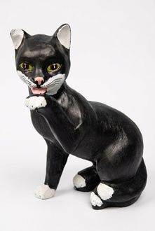 Licking a paw sitting cat figure in motley black white colored with green eyes 48x40cm