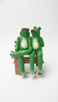 Two green colored bright frogs resting on a bench sculpture 47cm height c491