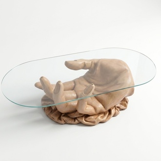 Oval glass coffee table with a decorative massive hand figure 45cm